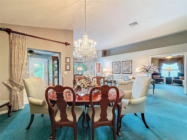 carpeted dining space featuring vaulted ceiling and ceiling fan with notable chandelier