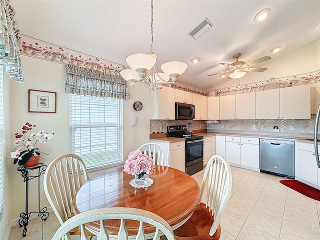 dining area featuring a textured ceiling, light tile patterned floors, ceiling fan with notable chandelier, and vaulted ceiling