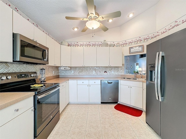 kitchen featuring appliances with stainless steel finishes, a textured ceiling, white cabinetry, lofted ceiling, and light tile patterned floors