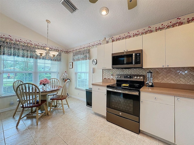 kitchen with vaulted ceiling, decorative light fixtures, stainless steel appliances, and plenty of natural light