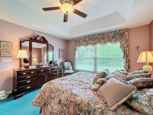 bedroom featuring ceiling fan, a raised ceiling, carpet, and a textured ceiling