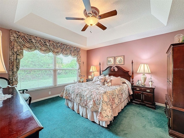 carpeted bedroom featuring ceiling fan, a raised ceiling, and a textured ceiling