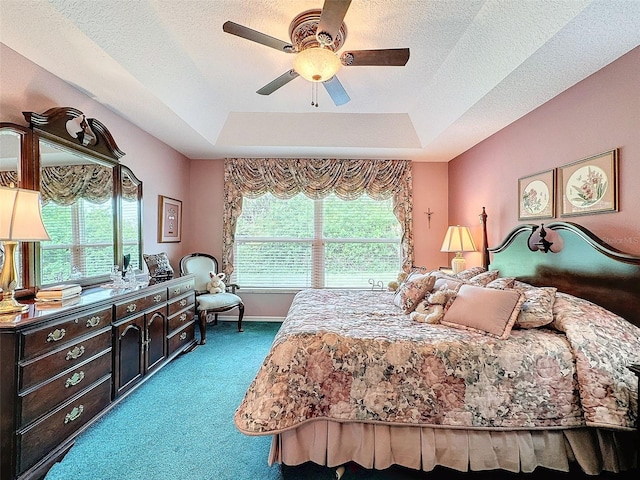 carpeted bedroom with ceiling fan, a raised ceiling, and a textured ceiling