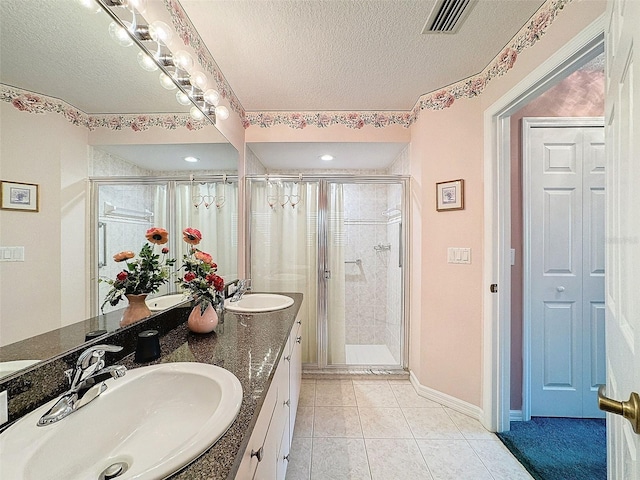 bathroom featuring a shower with door, vanity, a textured ceiling, and tile patterned flooring