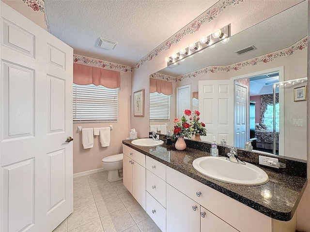 bathroom with vanity, toilet, tile patterned floors, and a textured ceiling