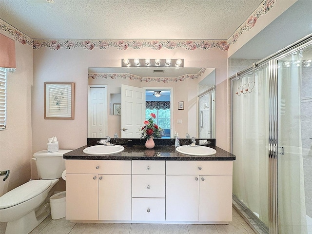 bathroom with a textured ceiling, toilet, vanity, an enclosed shower, and tile patterned flooring