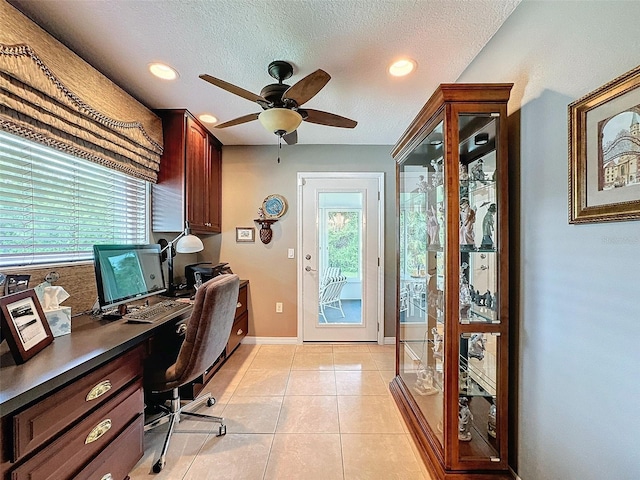 office space with a textured ceiling, built in desk, light tile patterned floors, and ceiling fan