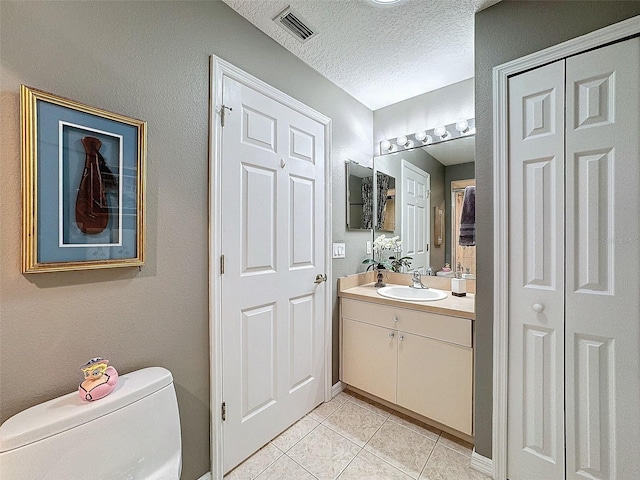 bathroom featuring vanity, a textured ceiling, toilet, and tile patterned flooring