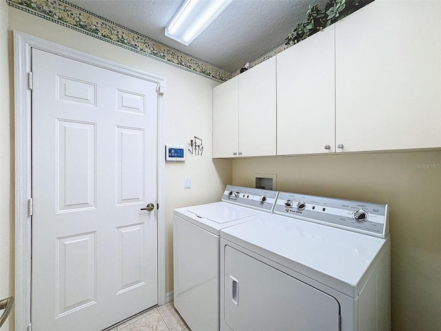 laundry area featuring independent washer and dryer, a textured ceiling, cabinets, and light tile patterned floors