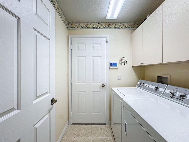 clothes washing area with cabinets, a textured ceiling, washing machine and clothes dryer, and light tile patterned floors