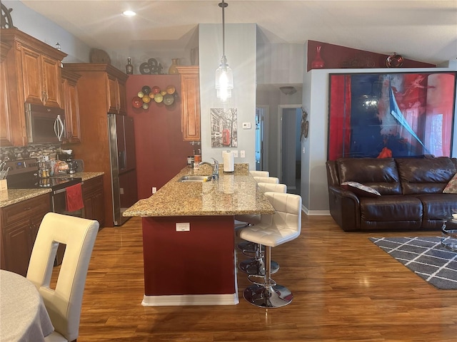 kitchen featuring appliances with stainless steel finishes, dark wood-type flooring, tasteful backsplash, a kitchen bar, and sink