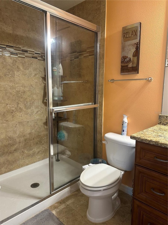 bathroom with vanity, a shower with shower door, toilet, and tile patterned floors