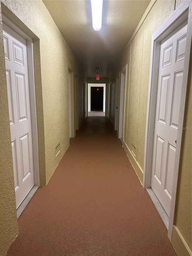 hall featuring a textured ceiling and carpet