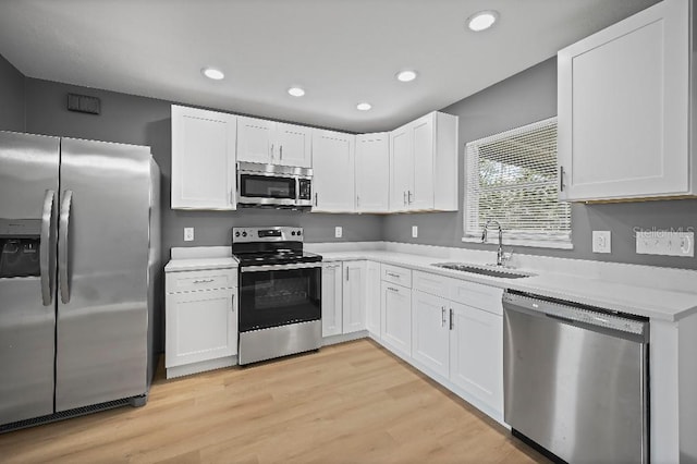 kitchen featuring sink, white cabinets, light hardwood / wood-style floors, and appliances with stainless steel finishes