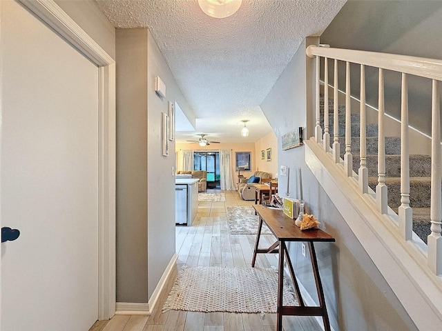 hall with light hardwood / wood-style floors and a textured ceiling