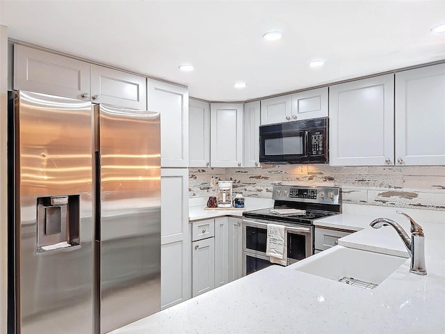 kitchen with tasteful backsplash, appliances with stainless steel finishes, light stone countertops, gray cabinetry, and sink