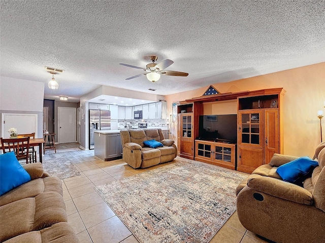 living area featuring light tile patterned floors, visible vents, a textured ceiling, and ceiling fan