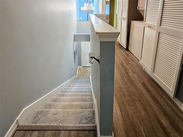 staircase with an inviting chandelier and wood-type flooring