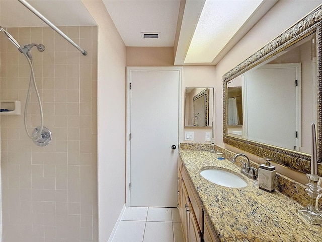 bathroom featuring tile patterned floors, visible vents, a tile shower, baseboards, and vanity