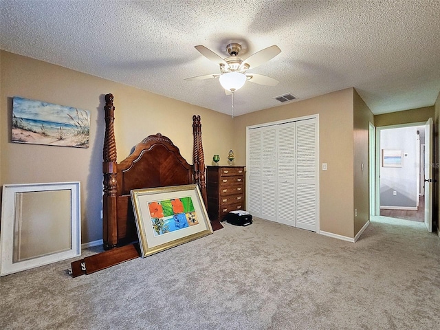 bedroom with visible vents, a ceiling fan, a textured ceiling, a closet, and carpet floors