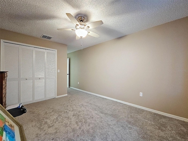 unfurnished bedroom featuring visible vents, a textured ceiling, a closet, carpet, and baseboards