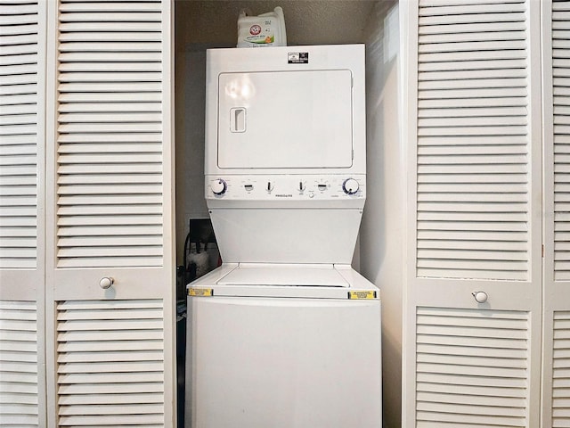 clothes washing area featuring a textured ceiling and stacked washer and dryer