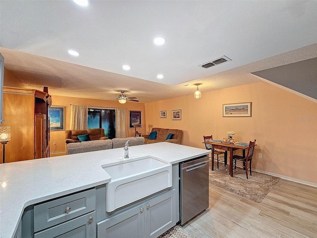 kitchen featuring light countertops, light wood-type flooring, open floor plan, and a sink