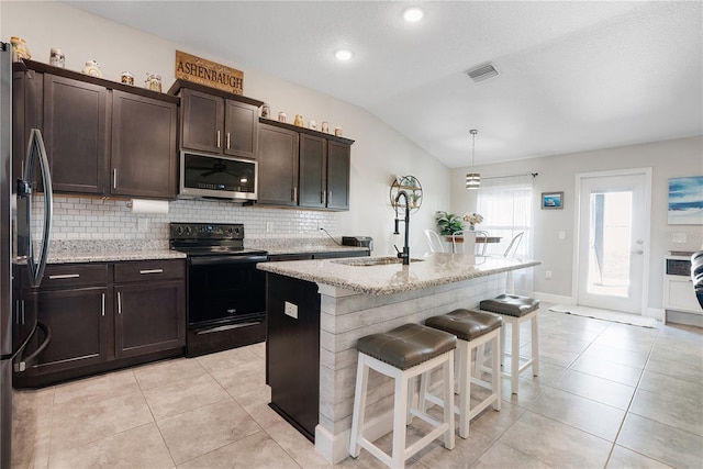 kitchen with black range with electric stovetop, sink, lofted ceiling, hanging light fixtures, and an island with sink