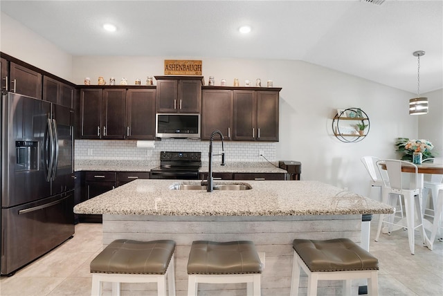 kitchen featuring a kitchen island with sink, stainless steel appliances, sink, vaulted ceiling, and decorative light fixtures