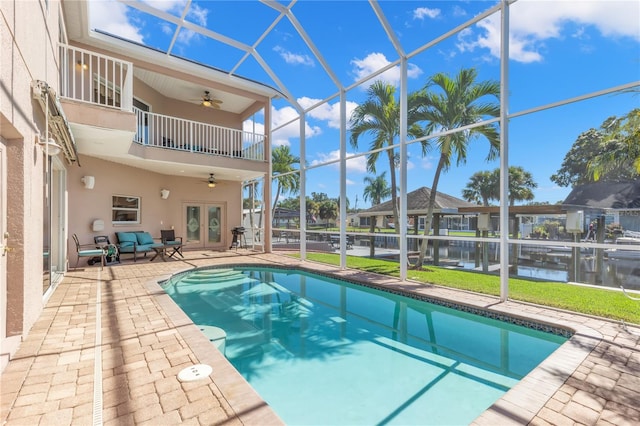 view of pool featuring ceiling fan, a patio, french doors, a lanai, and a water view