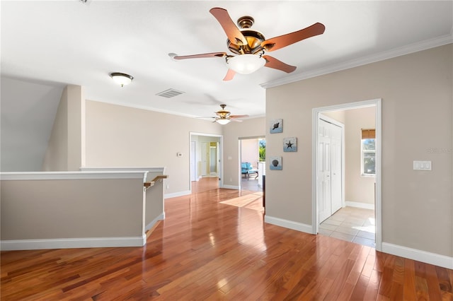 empty room featuring light wood-type flooring, crown molding, and ceiling fan