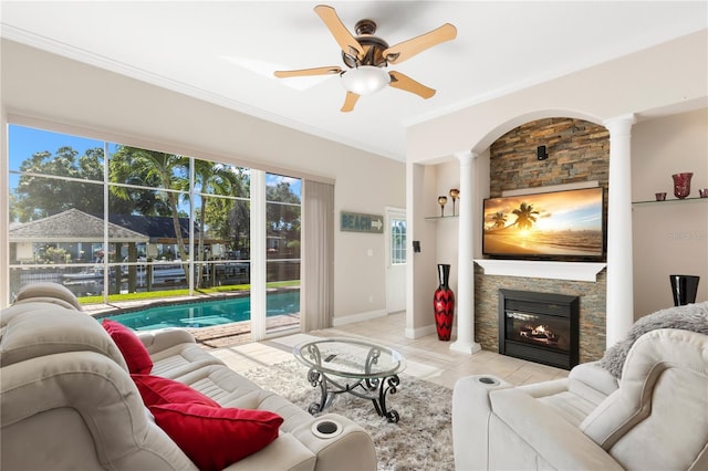 tiled living room with a fireplace, ornamental molding, decorative columns, and ceiling fan