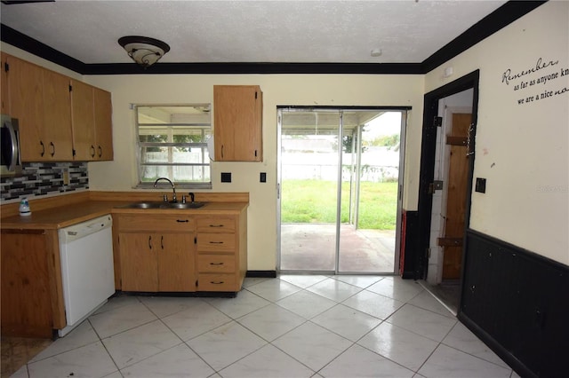 kitchen featuring white dishwasher, sink, a textured ceiling, and a healthy amount of sunlight