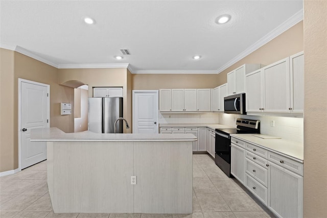 kitchen with white cabinets, an island with sink, light tile patterned floors, ornamental molding, and stainless steel appliances