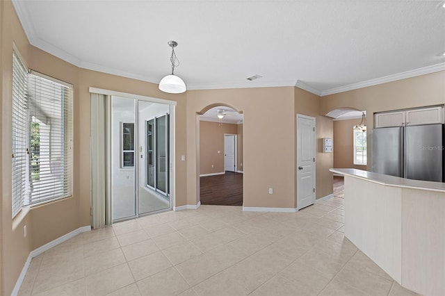 interior space with light tile patterned floors, stainless steel refrigerator, hanging light fixtures, and ornamental molding