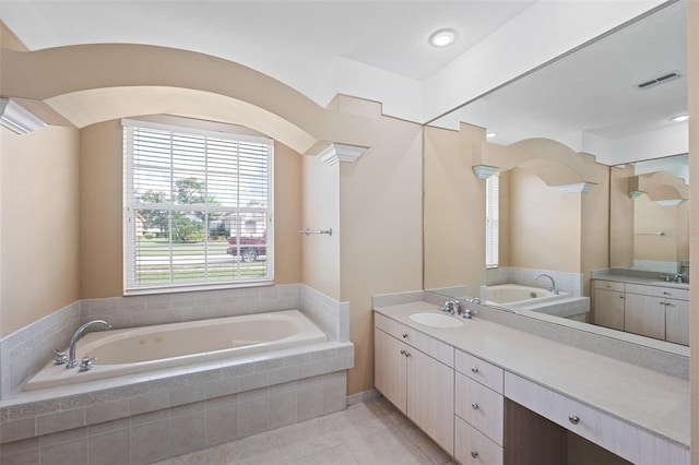 bathroom with vanity, tile patterned floors, decorative columns, and a relaxing tiled tub