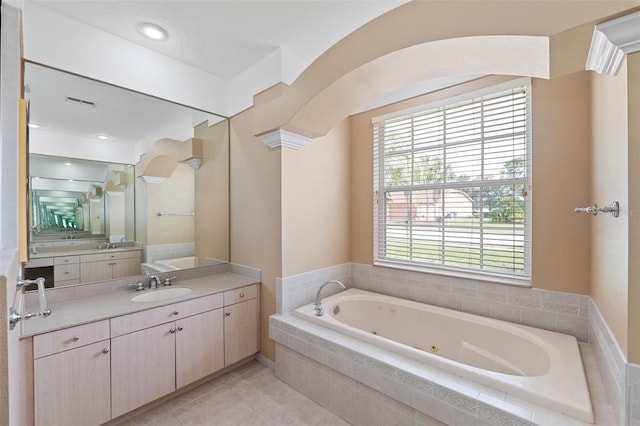 bathroom with decorative columns, tiled bath, vanity, and tile patterned floors