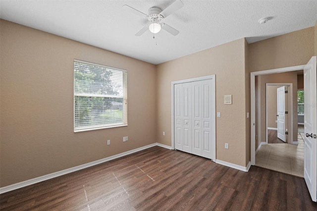 unfurnished bedroom with dark hardwood / wood-style floors, ceiling fan, and a closet