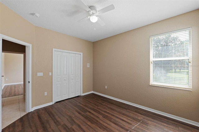 unfurnished bedroom with ceiling fan, multiple windows, and dark wood-type flooring