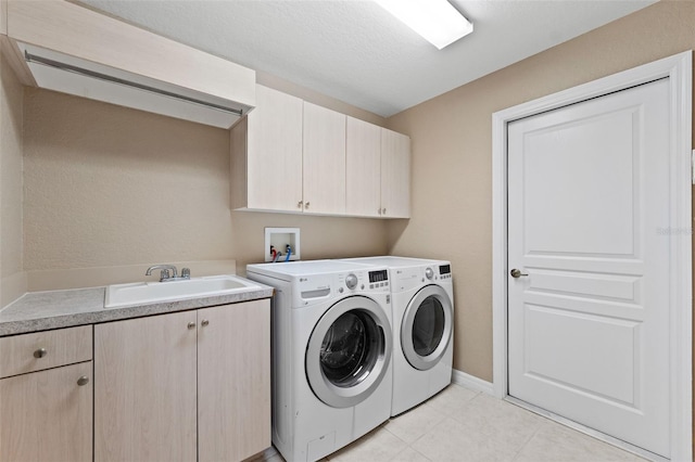 clothes washing area featuring a textured ceiling, washer and clothes dryer, sink, and cabinets