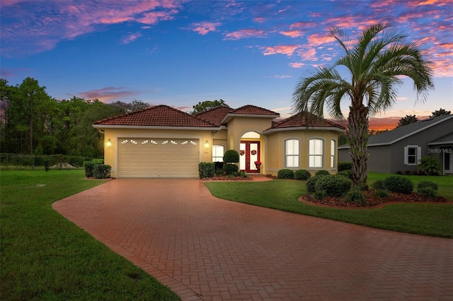 mediterranean / spanish home with a garage and a lawn