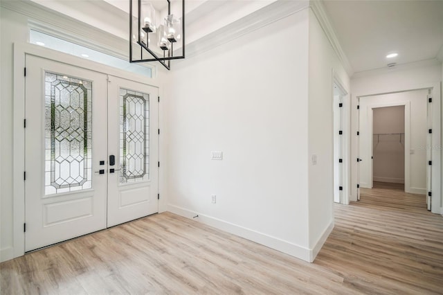 entryway featuring french doors, ornamental molding, an inviting chandelier, and light wood-type flooring