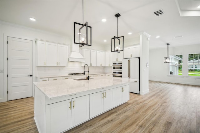 kitchen featuring a kitchen island with sink, light hardwood / wood-style flooring, and white cabinets