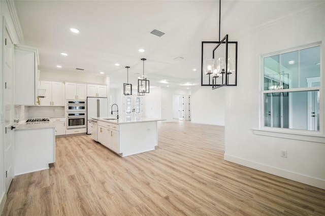 kitchen with light hardwood / wood-style flooring, an island with sink, sink, pendant lighting, and white cabinets