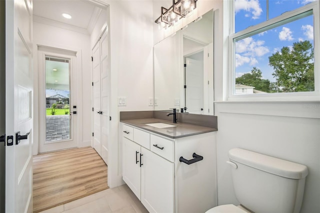 bathroom with toilet, crown molding, hardwood / wood-style floors, and vanity