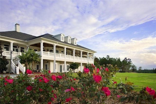 back of property with a balcony and a lawn