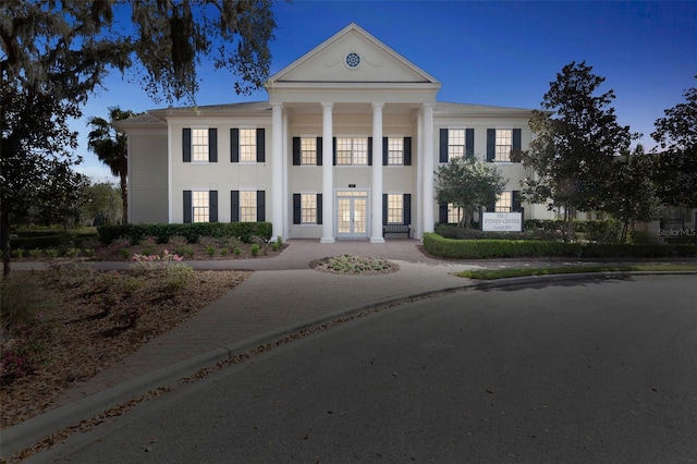 neoclassical home with french doors and stucco siding