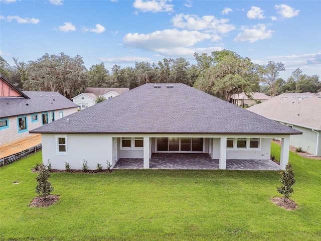 back of house with a patio, a lawn, roof with shingles, a residential view, and stucco siding