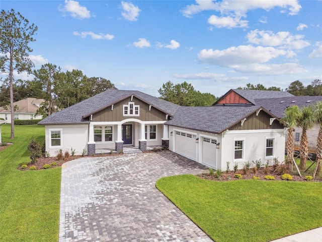 view of front of house featuring decorative driveway, roof with shingles, board and batten siding, a front yard, and a garage