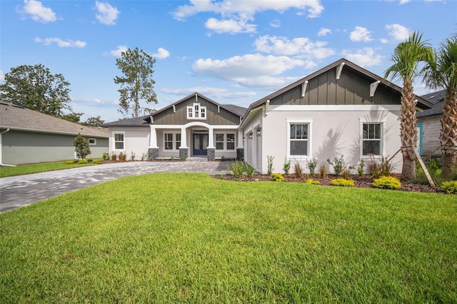 view of front of property with board and batten siding, a front lawn, and decorative driveway